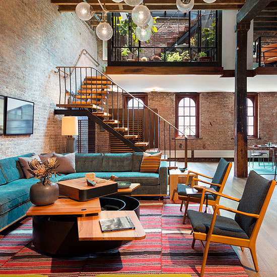 A historic warehouse loft in Tribeca becomes a warm, open residence with curated midcentury furnishings, soft carpets and rich fabrics contrasting the industrial space.